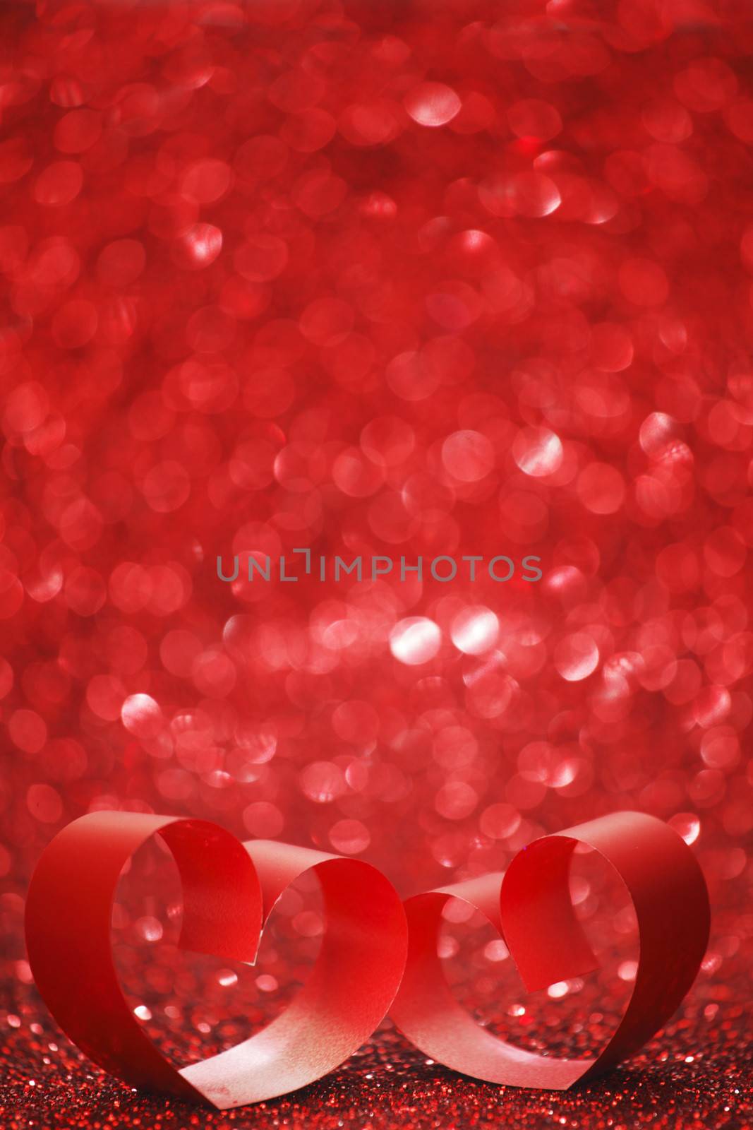 Red ribbon hearts on shiny glitter background