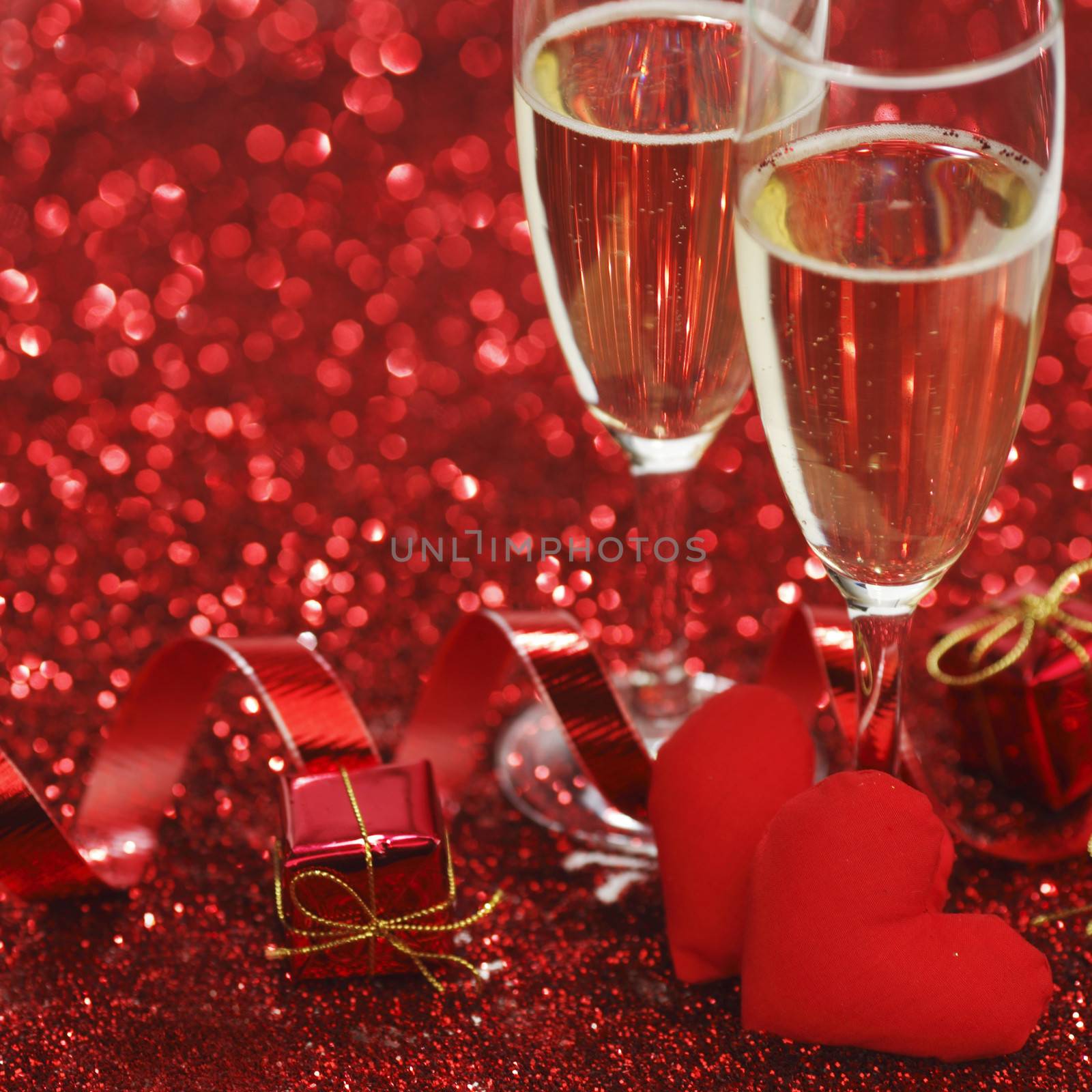 Champagne and valentines day gifts on red glitter background