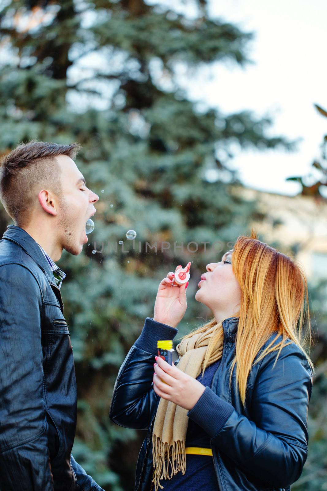Young loving couple starts soap bubbles in park outdoors