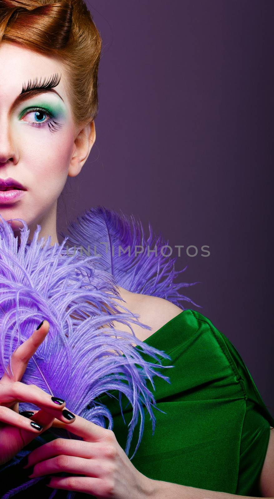 Attractive young girl with a fabulous makeup and feathers close-up portrait