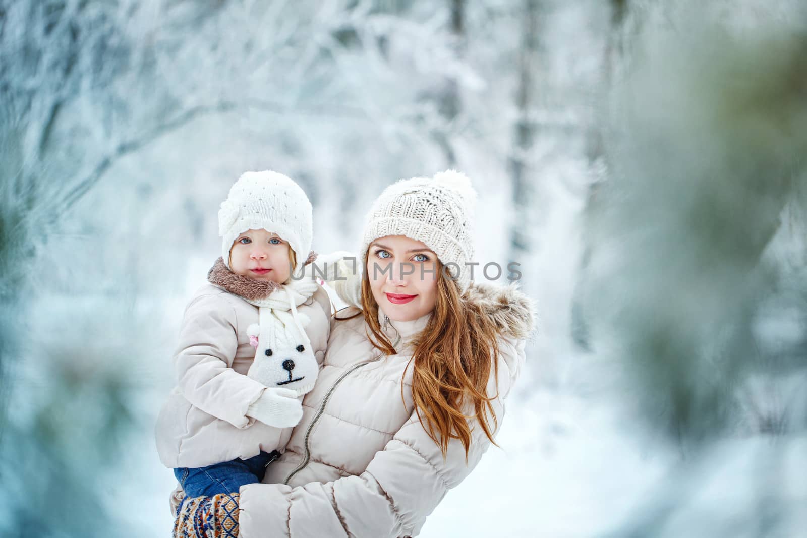 Mother holds daughter on hands in winter forest by Vagengeym