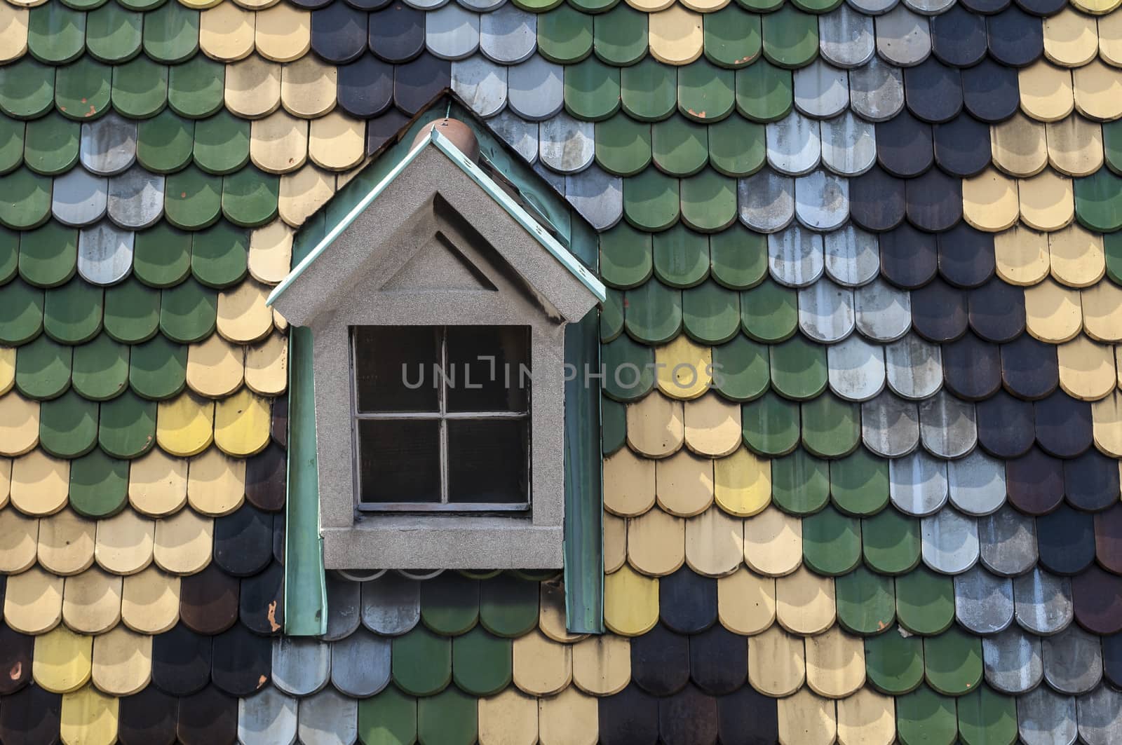 Detailed view of colorful roof shingles and window.