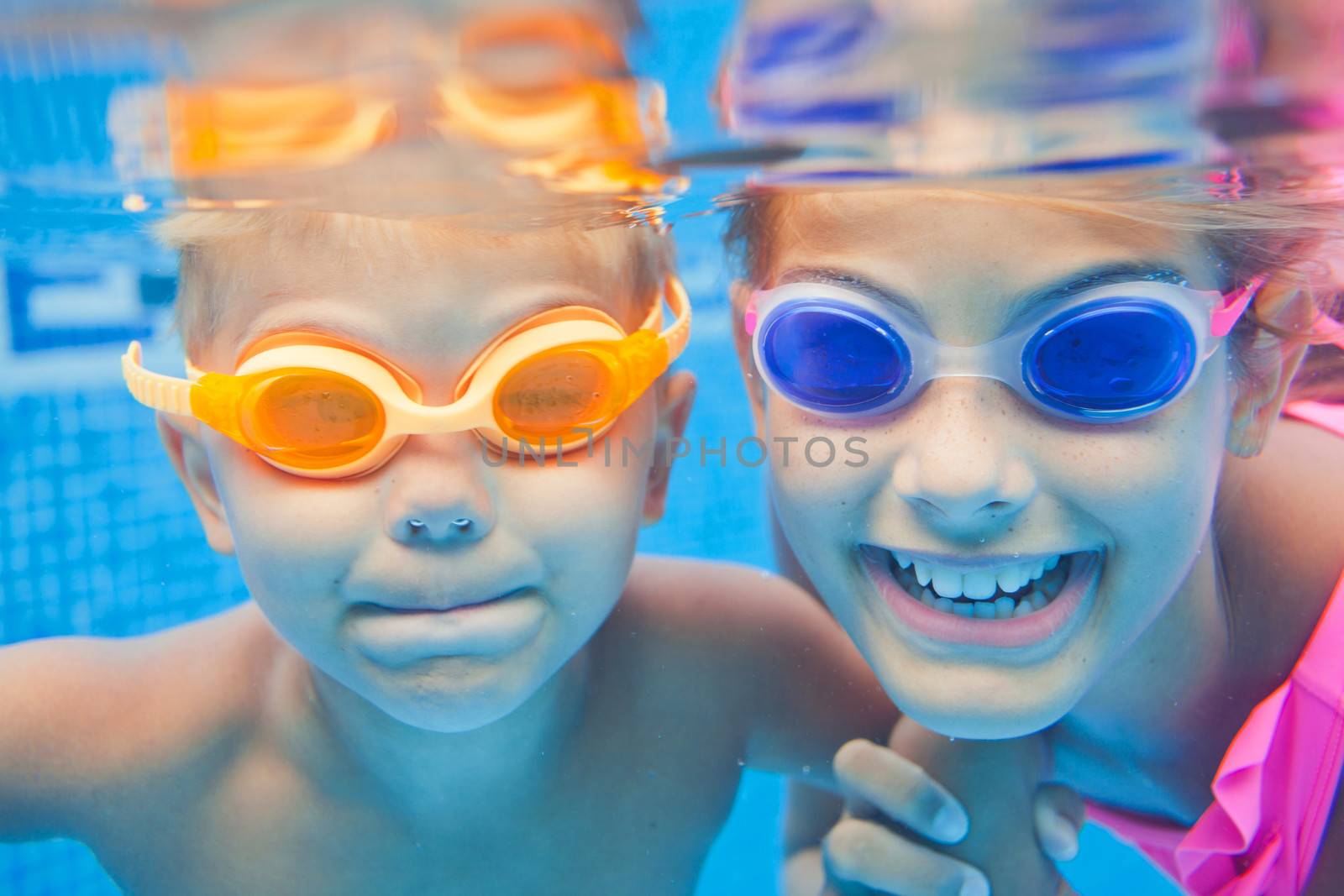 Close-up underwater portrait of the two cute smiling kids