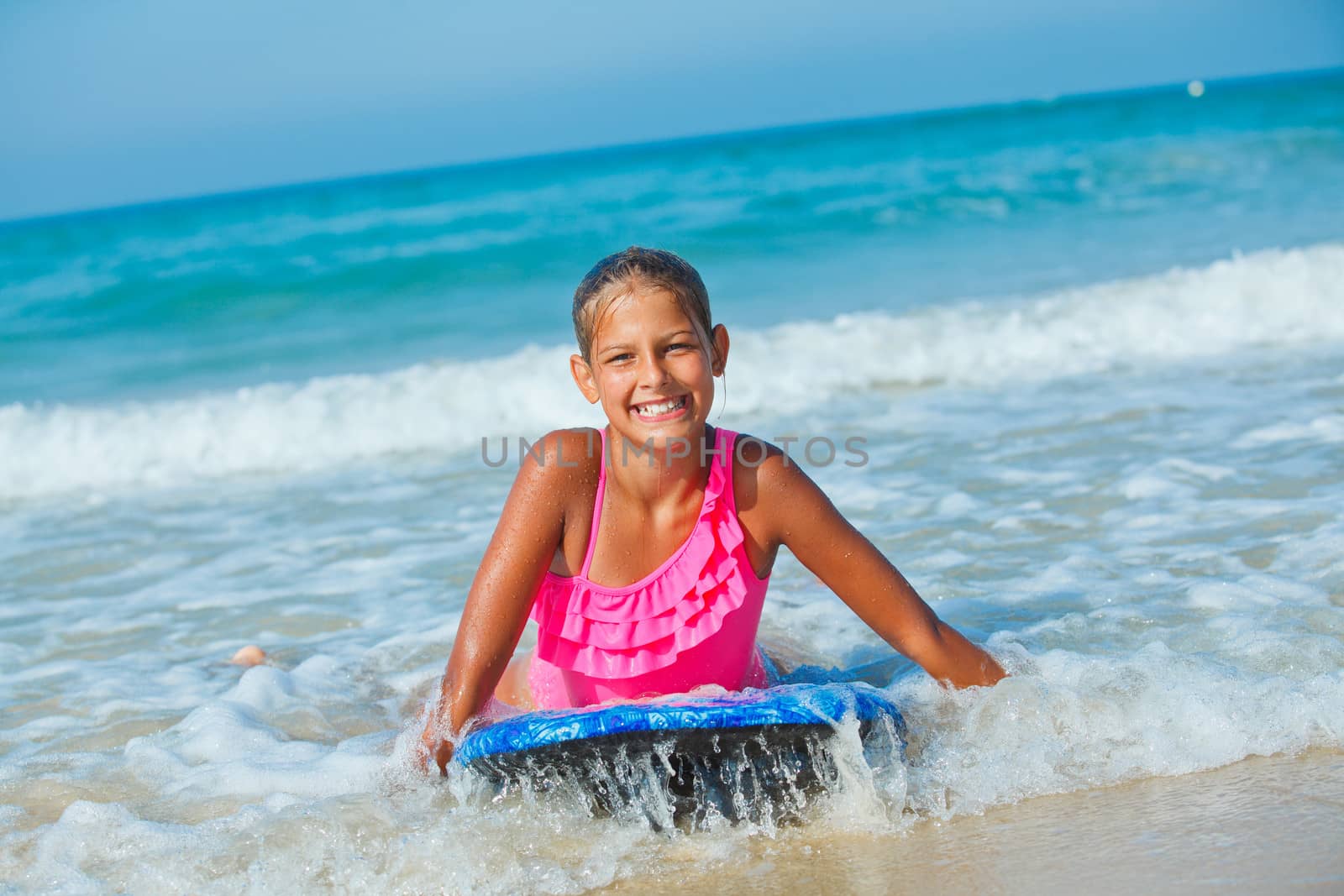 Summer vacation - Happy cute girl having fun with surfboard in the ocean