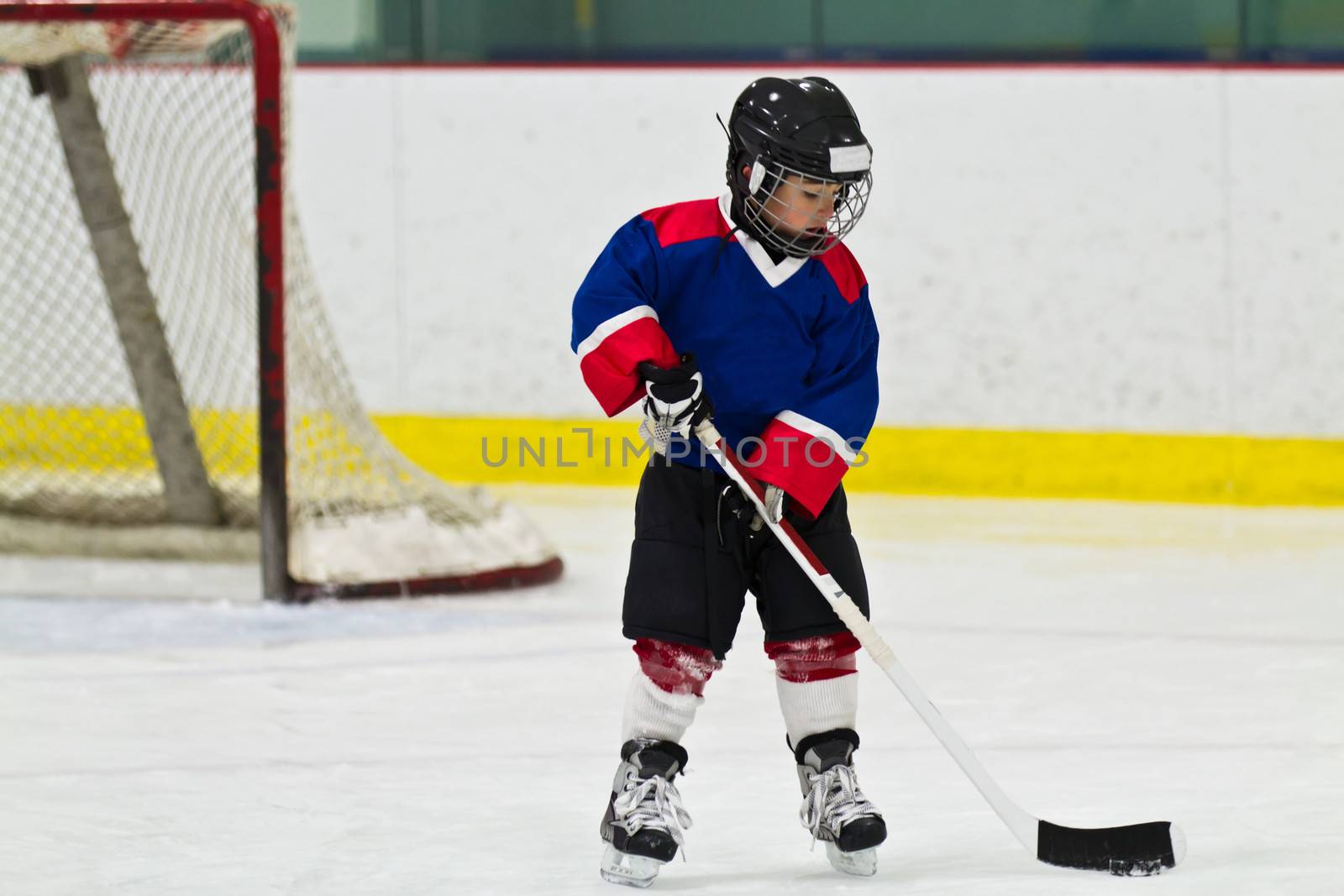 Child skating with a puck at ice hockey practice by bigjohn36