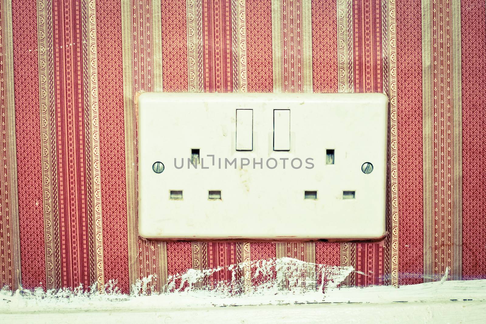 Twin power socket in a wall with retro wallpaper
