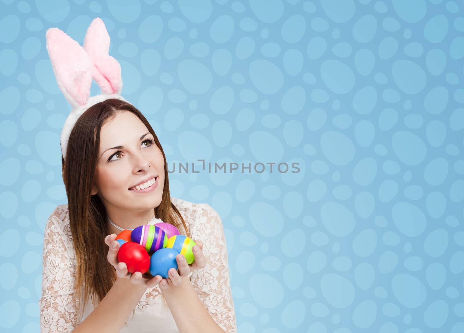 Excited girl holding bunch of painted eggs on blue background