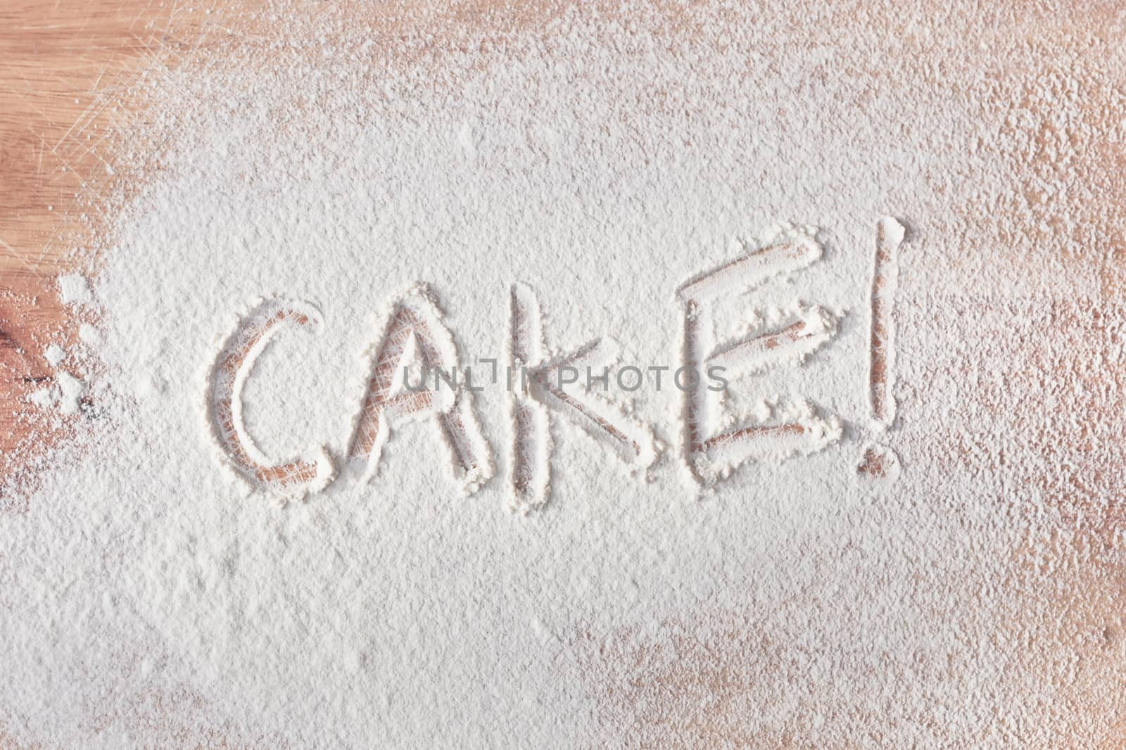 Cake written in flour on a wooden surface