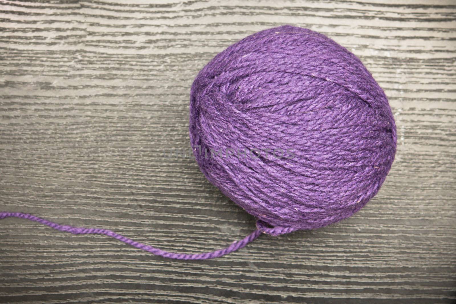 Ball of purple wool on a wooden surface