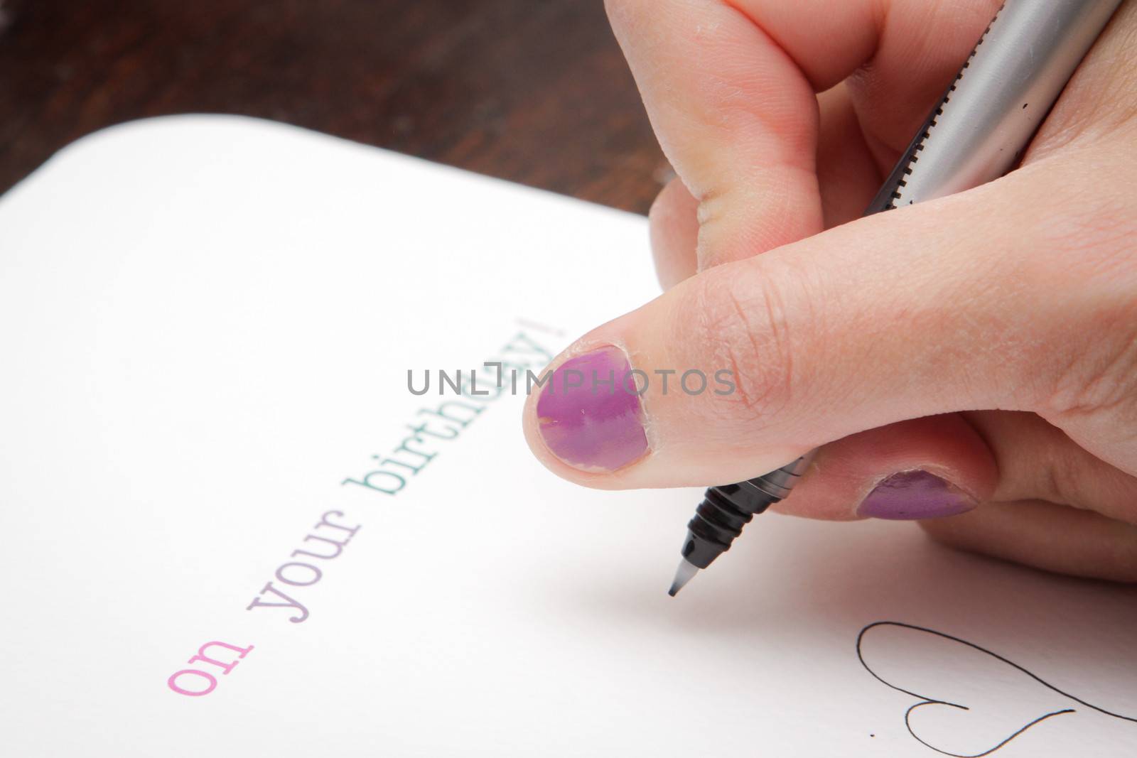 Close up of a woman's hand writing a birthday card