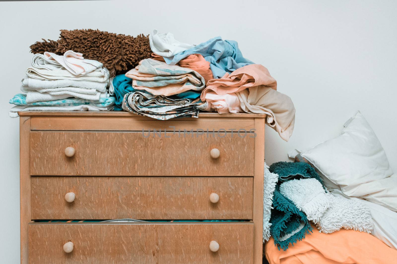 Piles of bed linen on a wooden chest of drawers