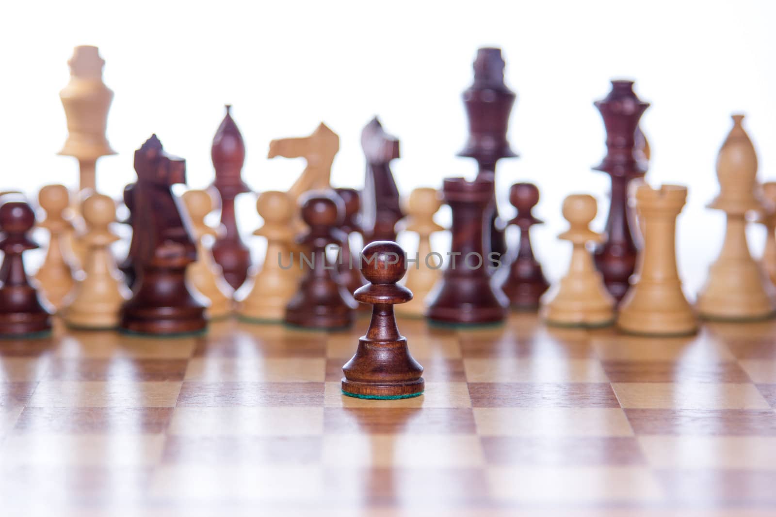 Beautiful chessboard with chessfigures in the back and a focused pawn in the front