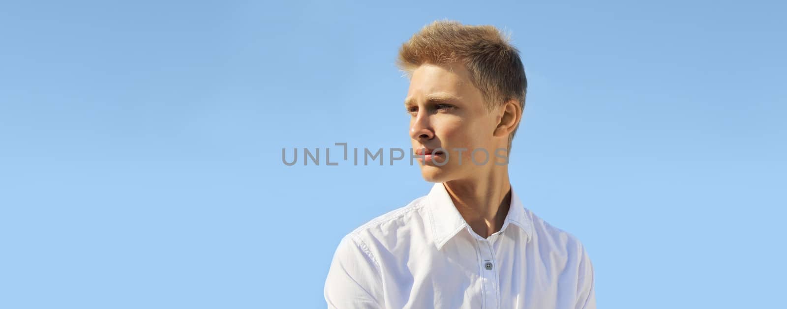 Handsome blond man on blue sky background at sunny day