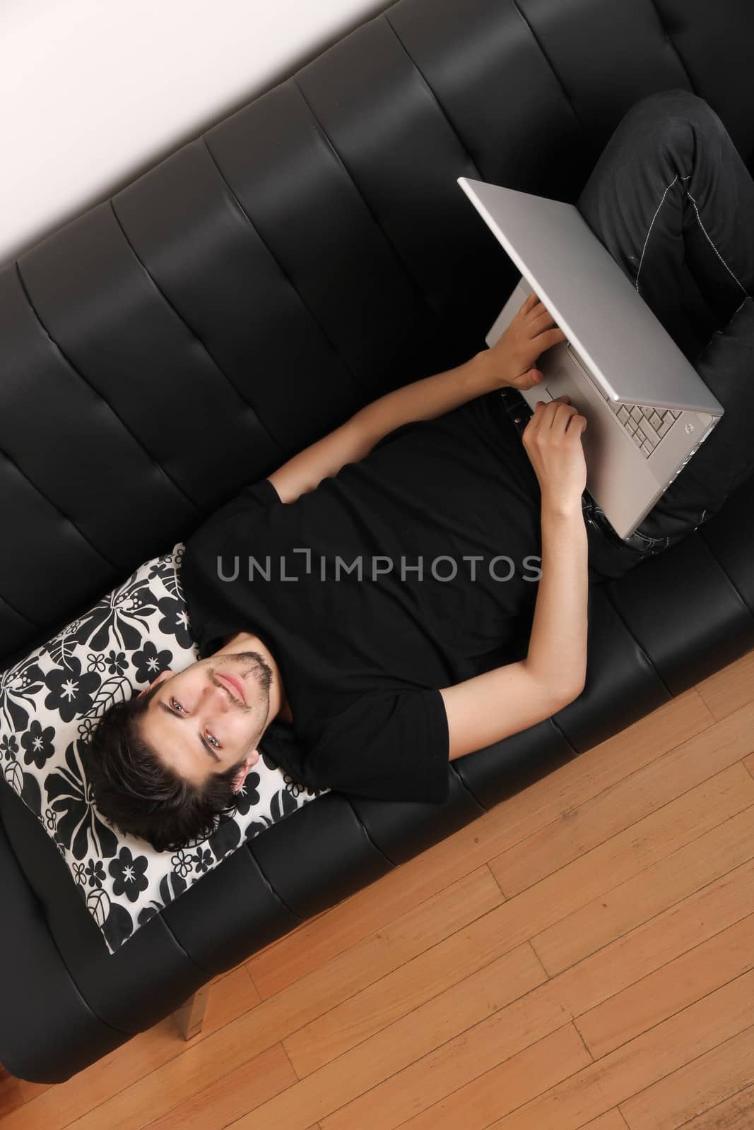 A young hispanic man with a laptop on the Sofa.