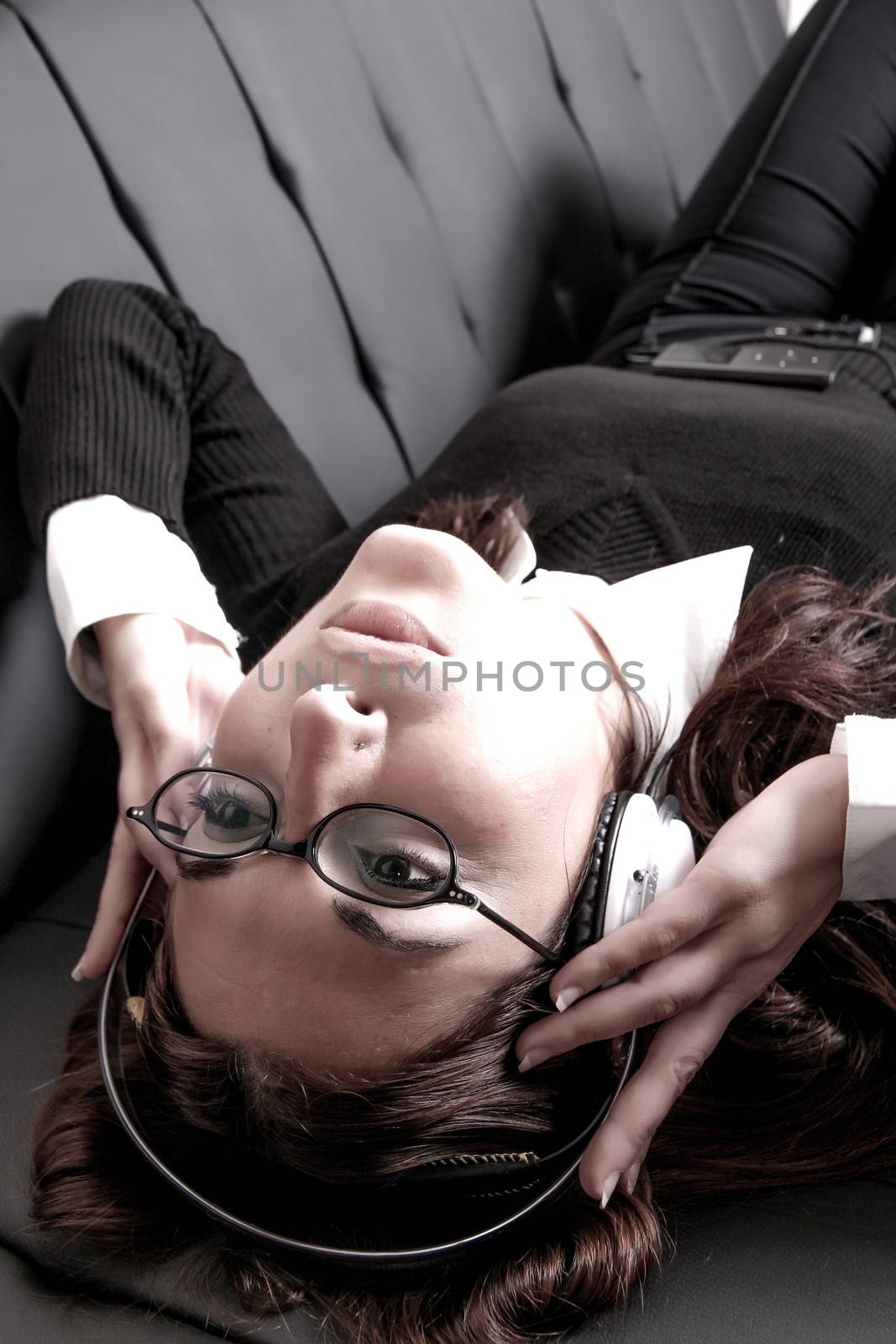 A girl listening to Music with headphones on the sofa.