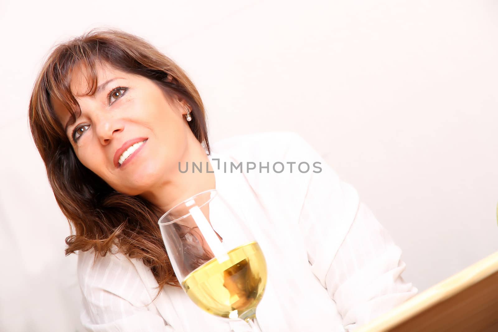 A beautiful mature woman with a glass of white wine.