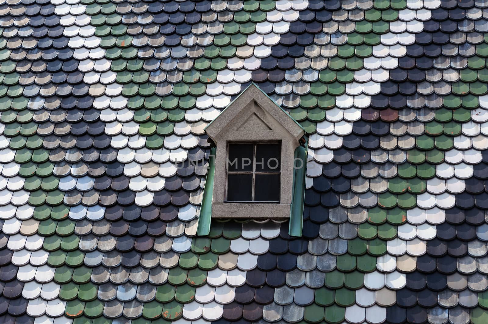 Detailed view of colorful roof shingles and window.