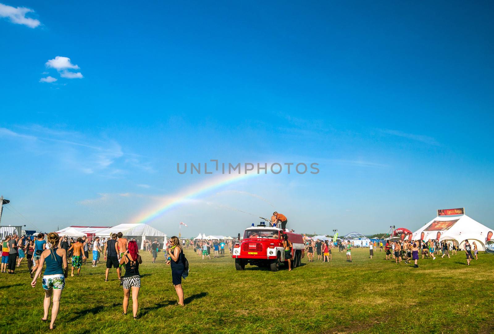 People enjoy the water from a fire truck on rainbow background at Mighty Sounds festival 19th of July, 2013