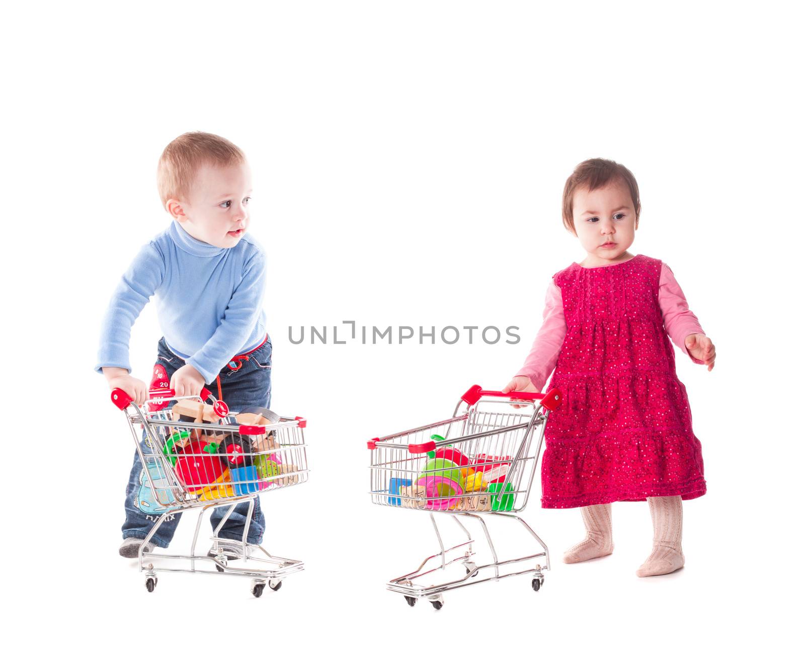 Boy and girl play with shopping trolley and toys, isolated on white