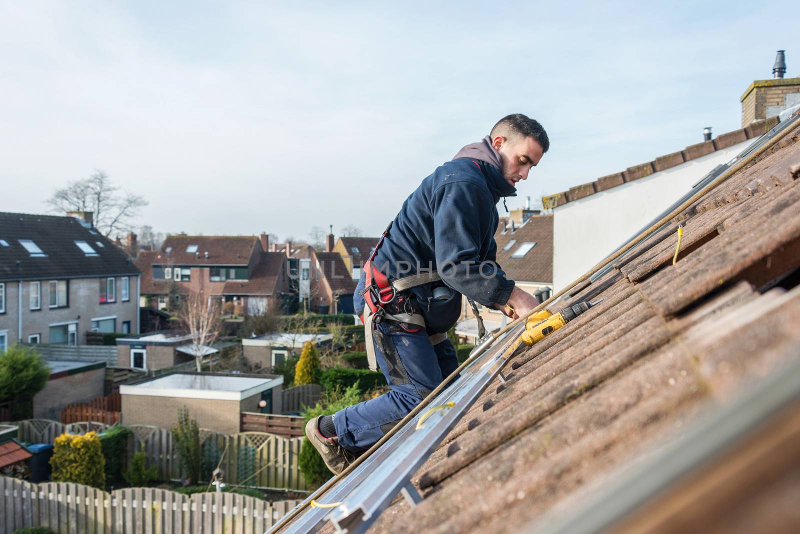 man making the construction for the solar panels high on the roof