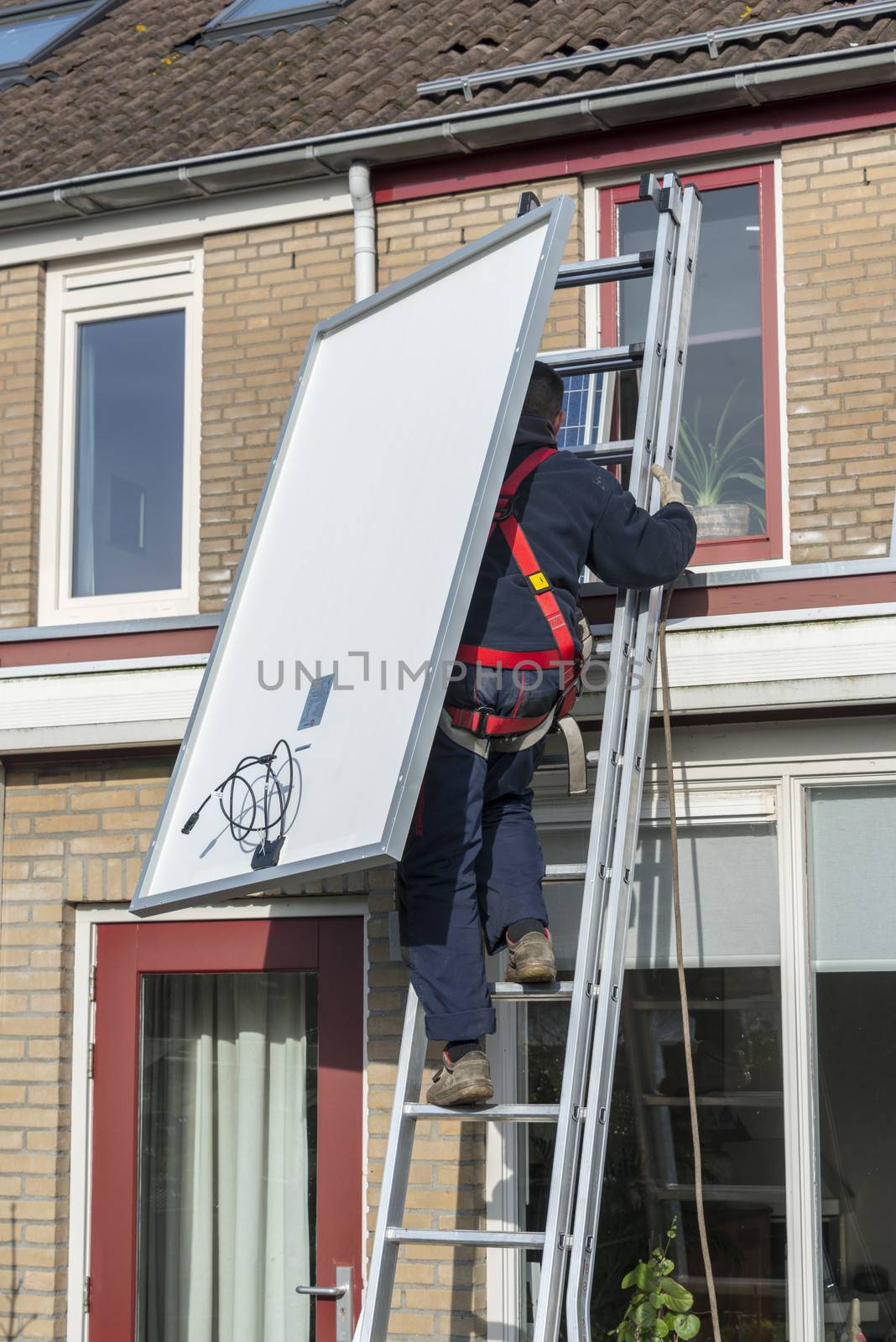 man climbing the ladder with solar panel by compuinfoto