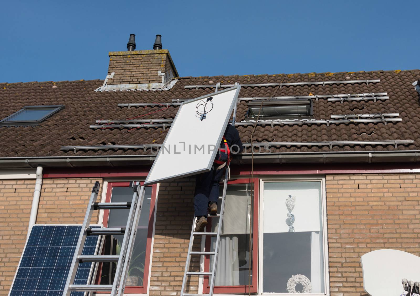 man climbing the ladder to the roof with solar panel