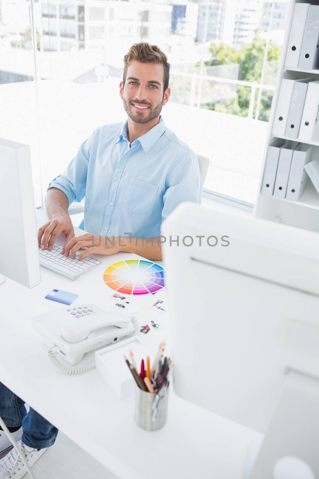 Portrait of a smiling casual male photo editor using computer in the office