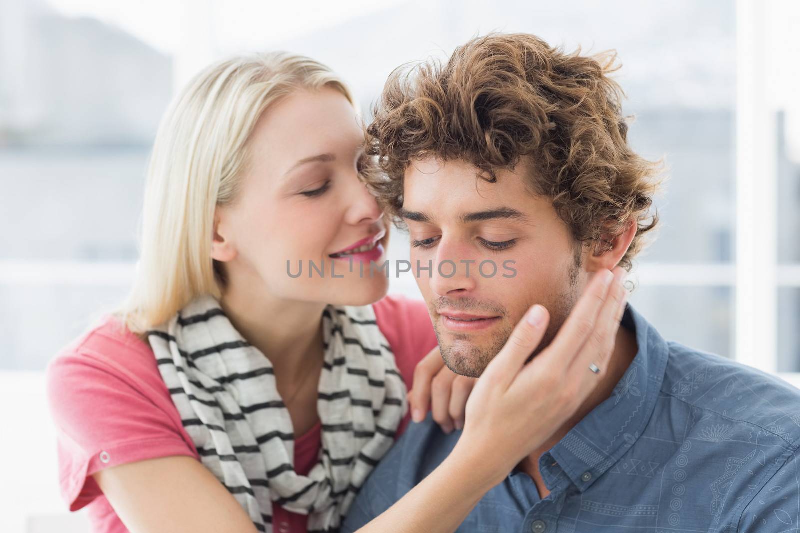 Happy casual young woman about to kiss man on his cheek