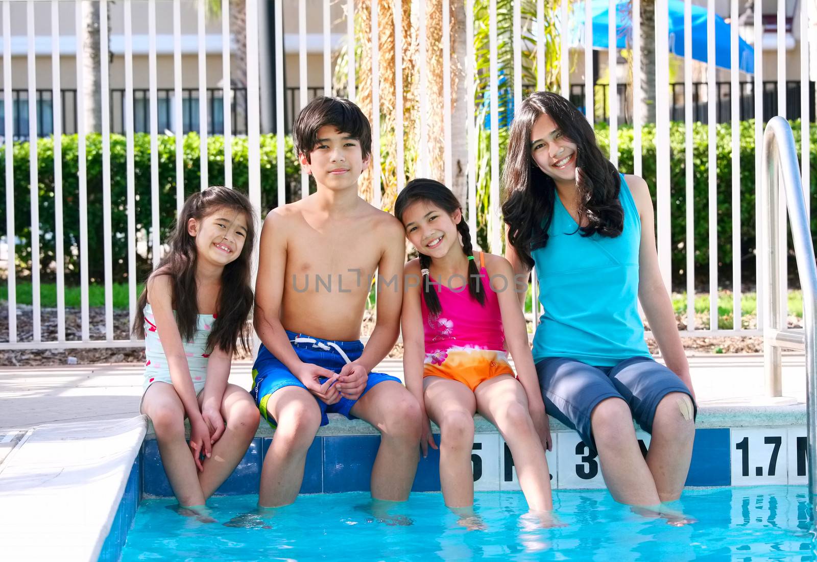 Four children, siblings,  enjoying the pool together