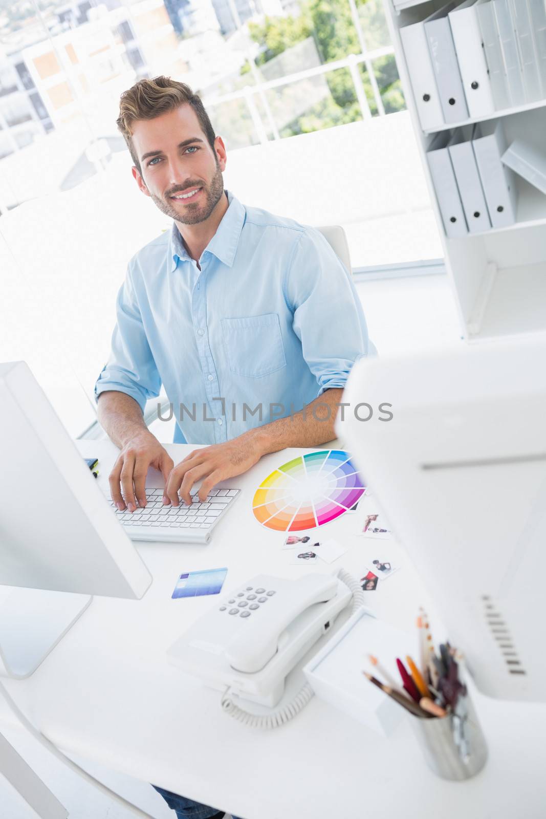 Portrait of a smiling casual male photo editor using computer in the office