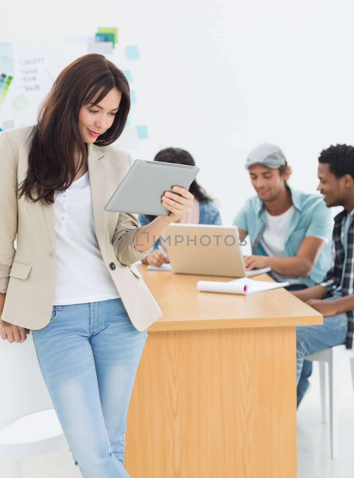 Woman using digital tablet with colleagues behind in office by Wavebreakmedia