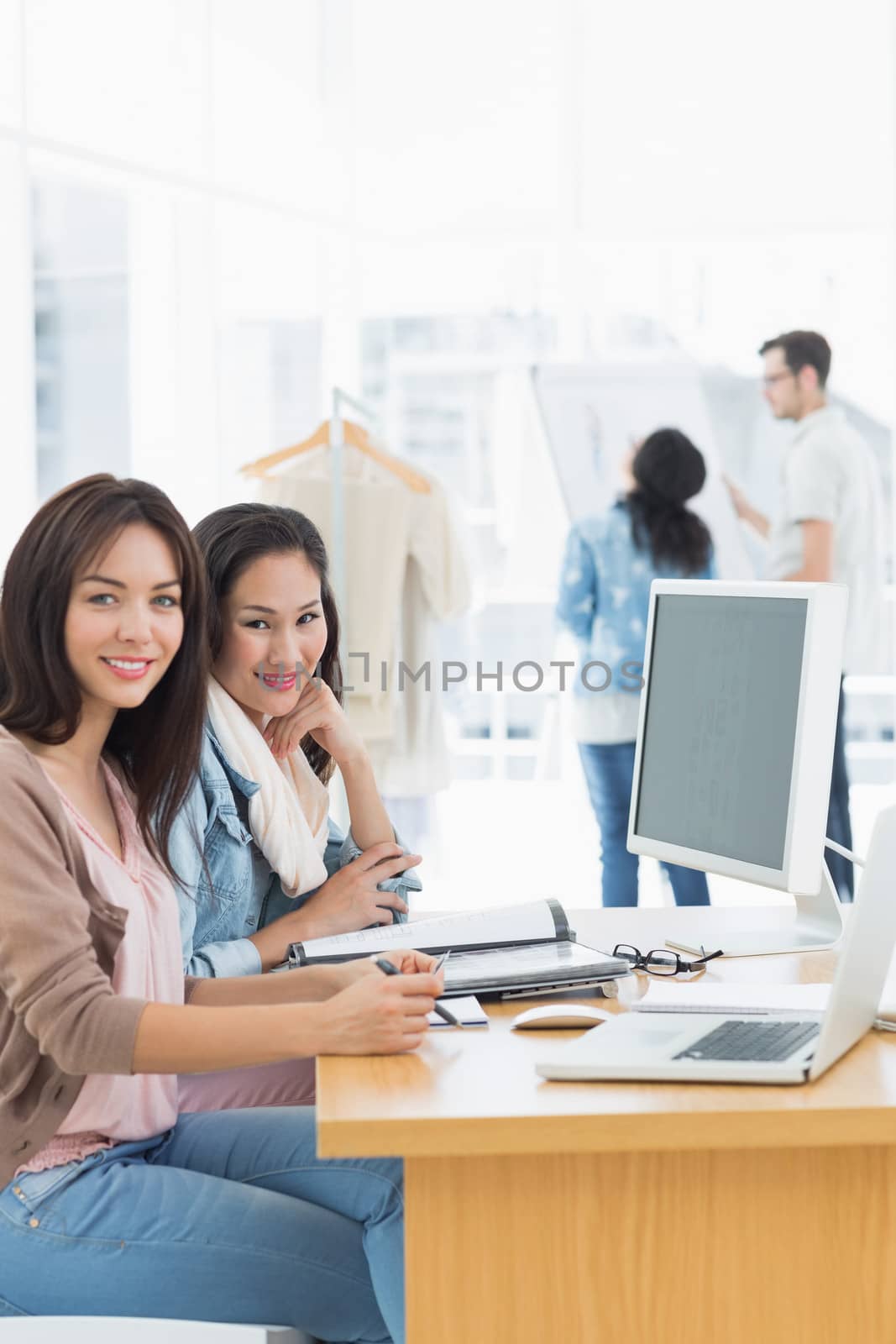 Portrait of two casual female artists working at desk in the creative office