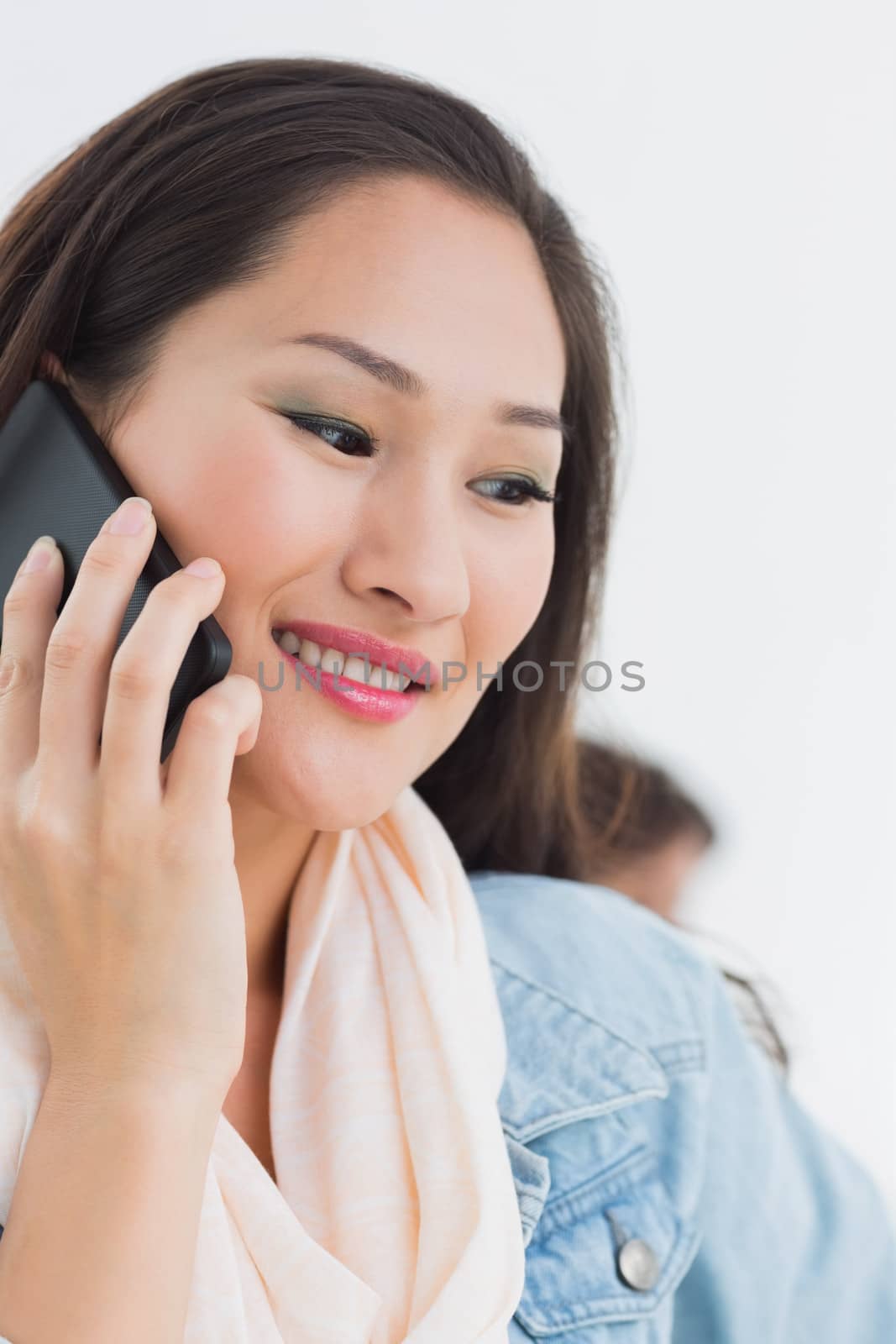Close-up of a beautiful casual young woman using mobile phone in a bright office