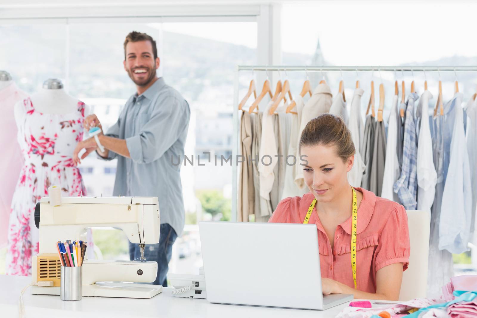 Woman using laptop with fashion designer working at studio by Wavebreakmedia