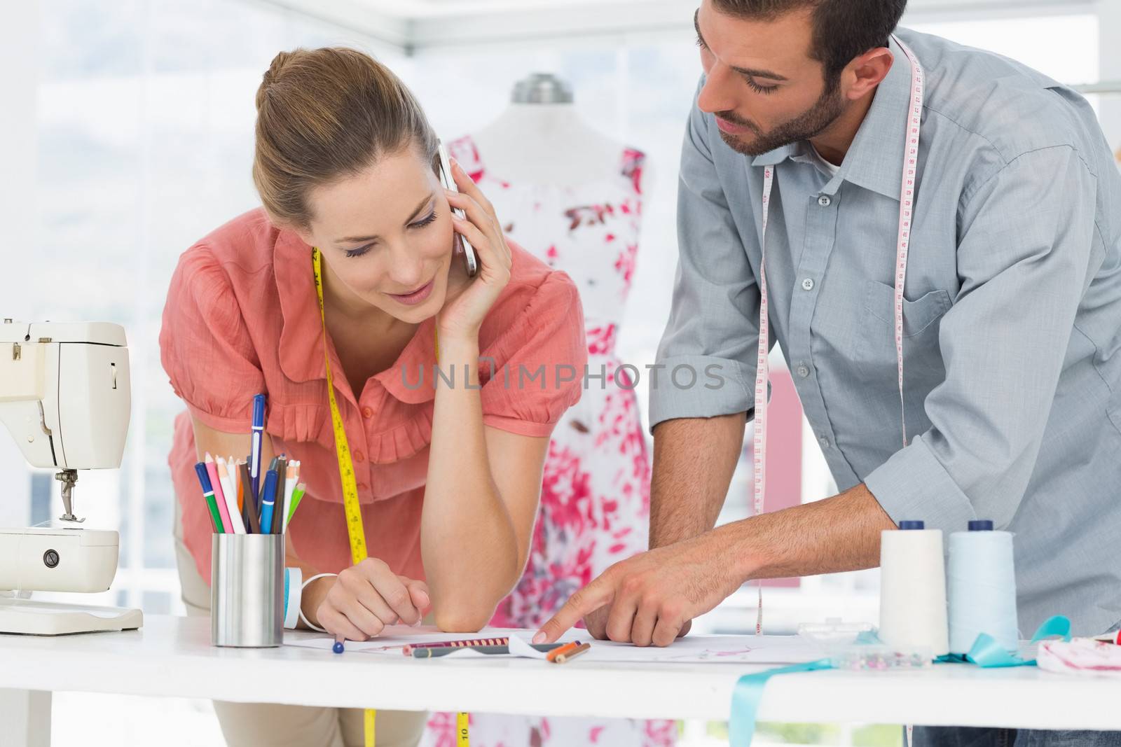 Male and female fashion designers at work in a bright studio