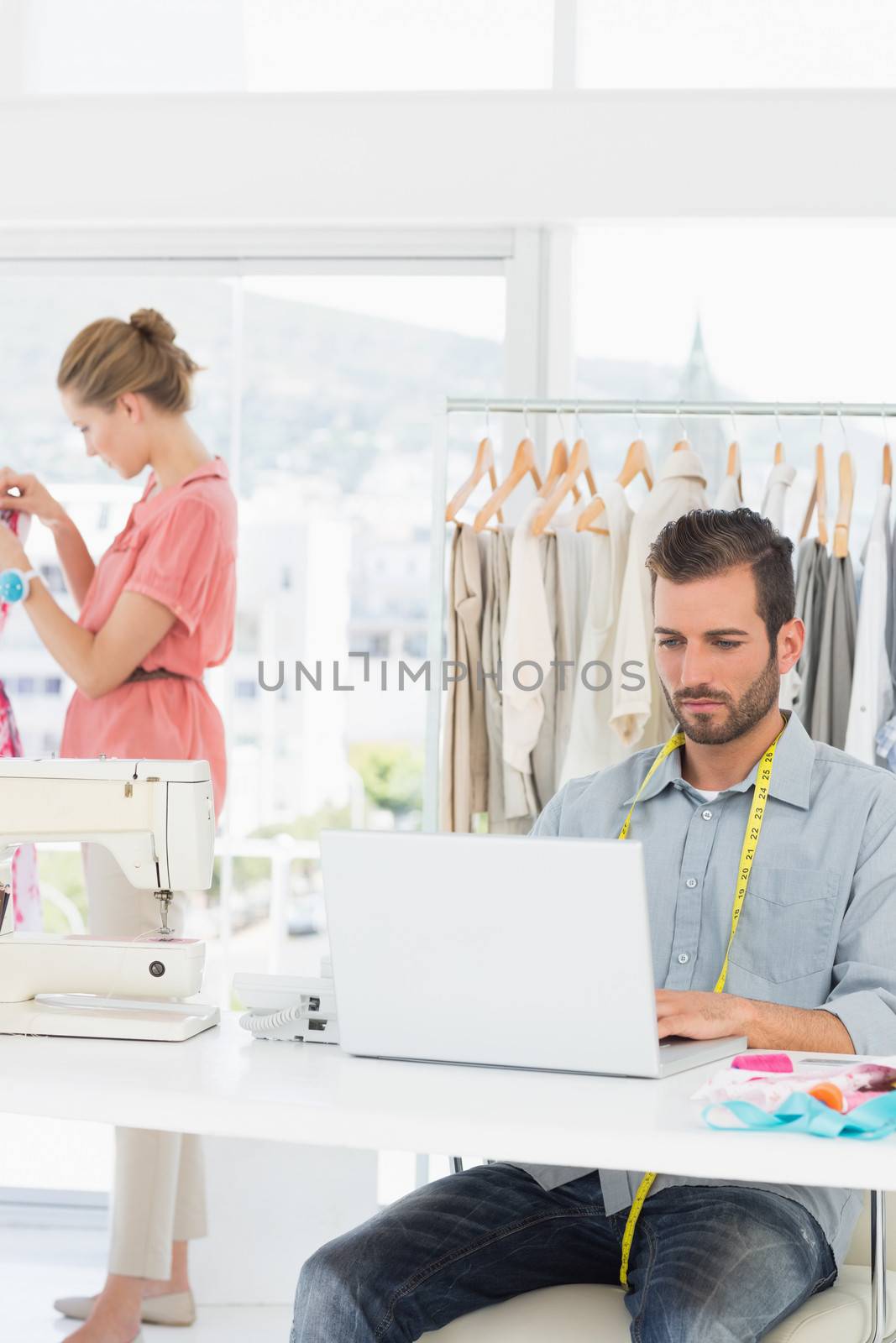 Man using laptop with fashion designer working at the studio by Wavebreakmedia