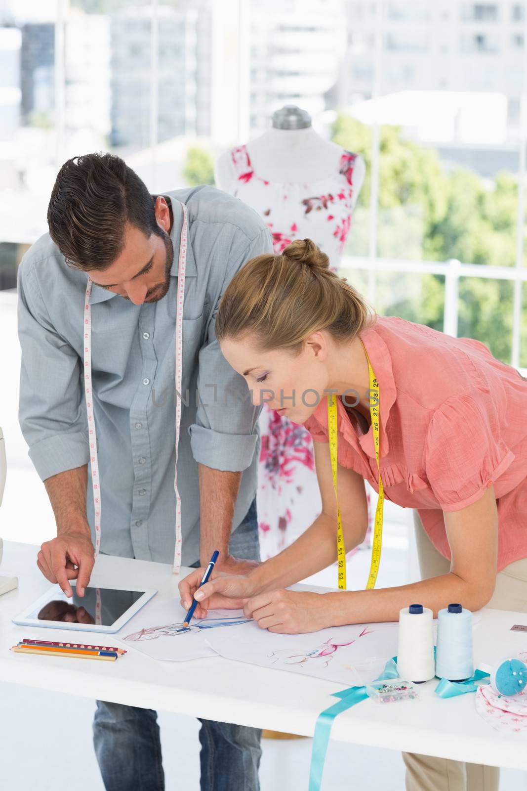 Male and female fashion designers using digital tablet in a bright studio