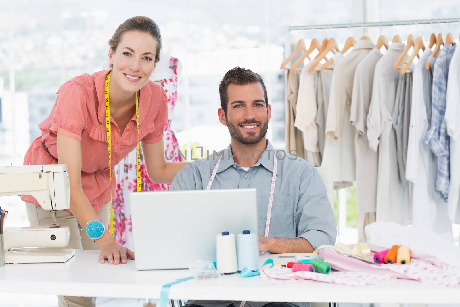 Male and female fashion designers with laptop at work in a bright studio