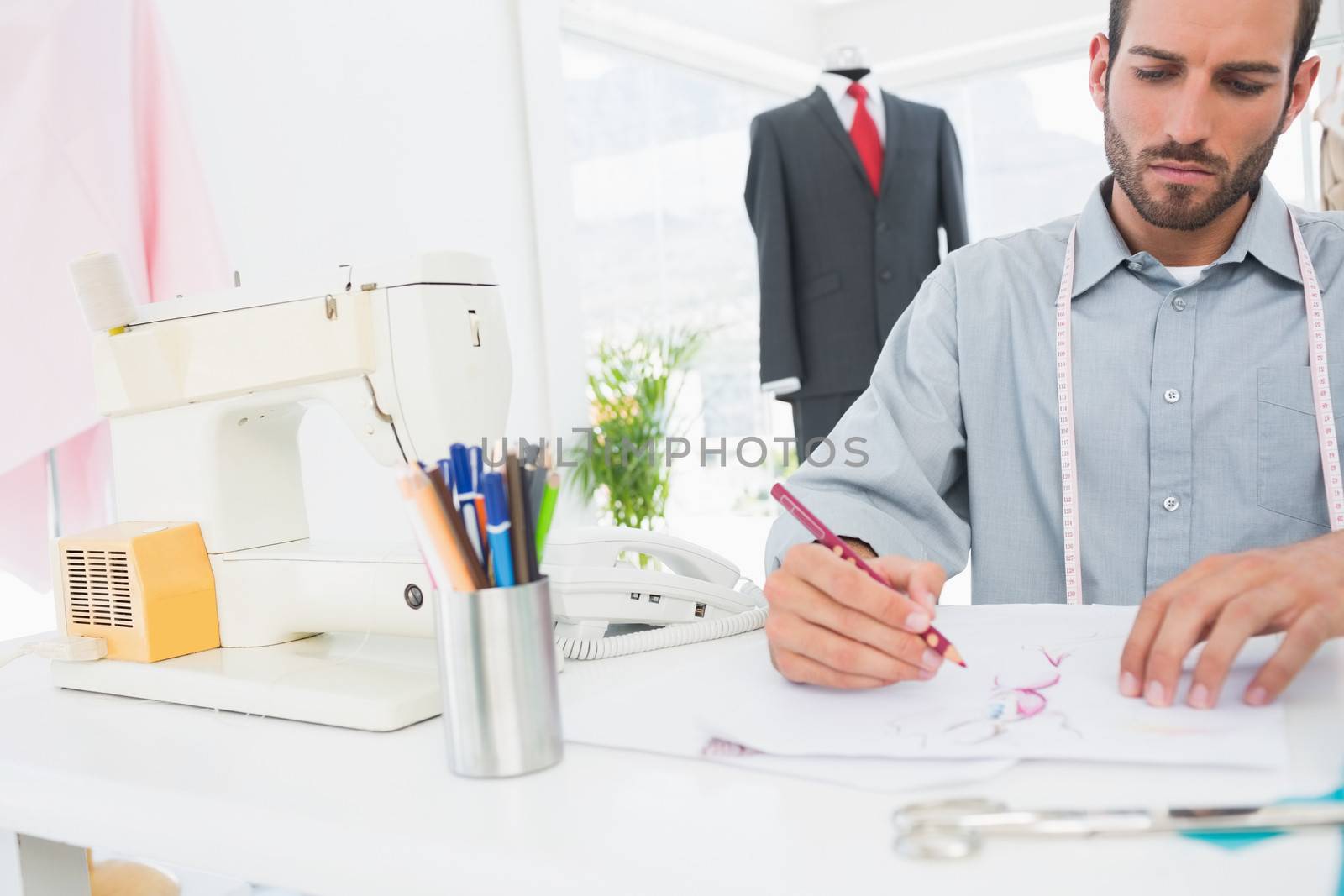 Young male fashion designer working on his designs in the studio