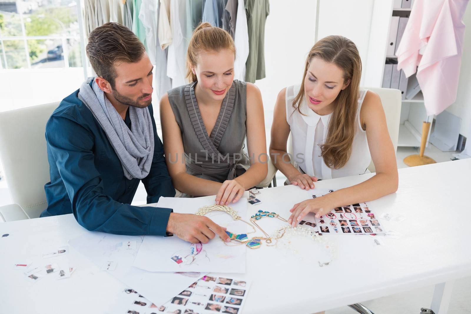 Three fashion designers discussing designs in a studio