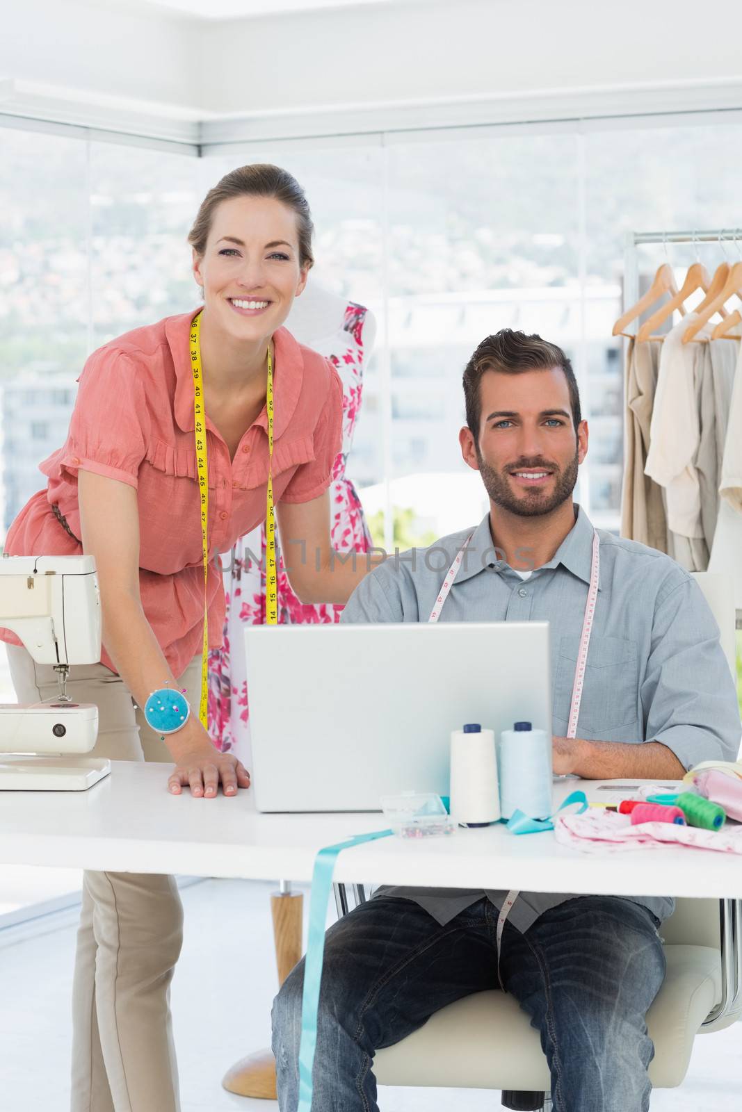 Male and female fashion designers with laptop at work in a bright studio