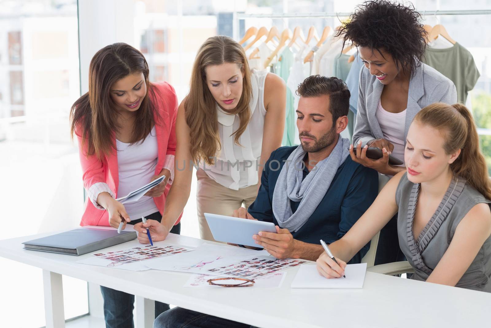 Group of fashion designers discussing designs in a studio