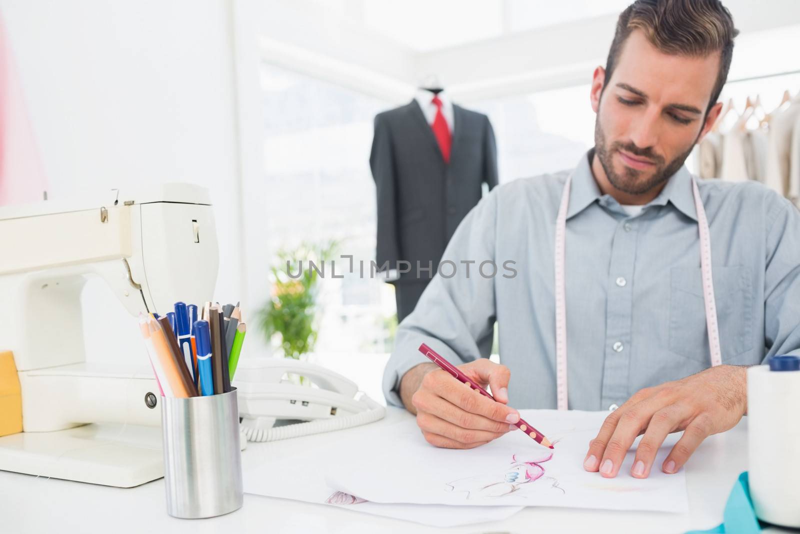 Young male fashion designer working on his designs in the studio