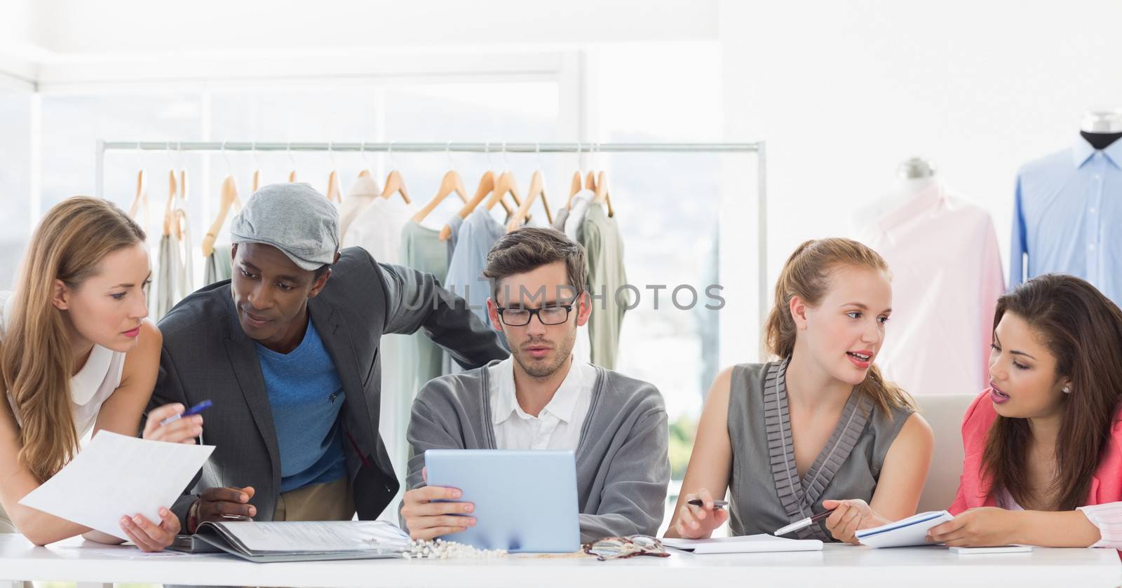 Group of fashion designers discussing designs in a studio