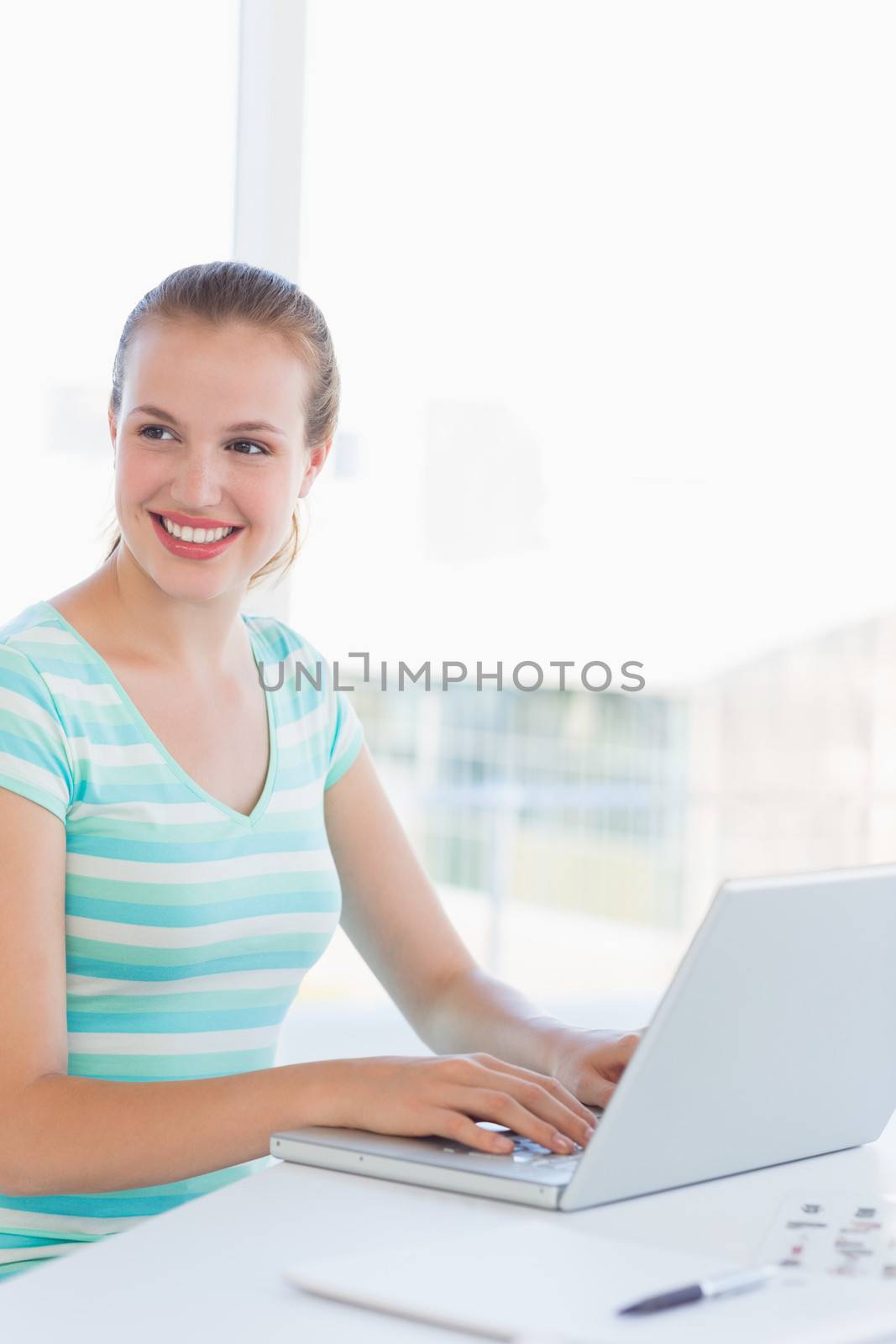 Young casual woman using laptop at a bright office by Wavebreakmedia