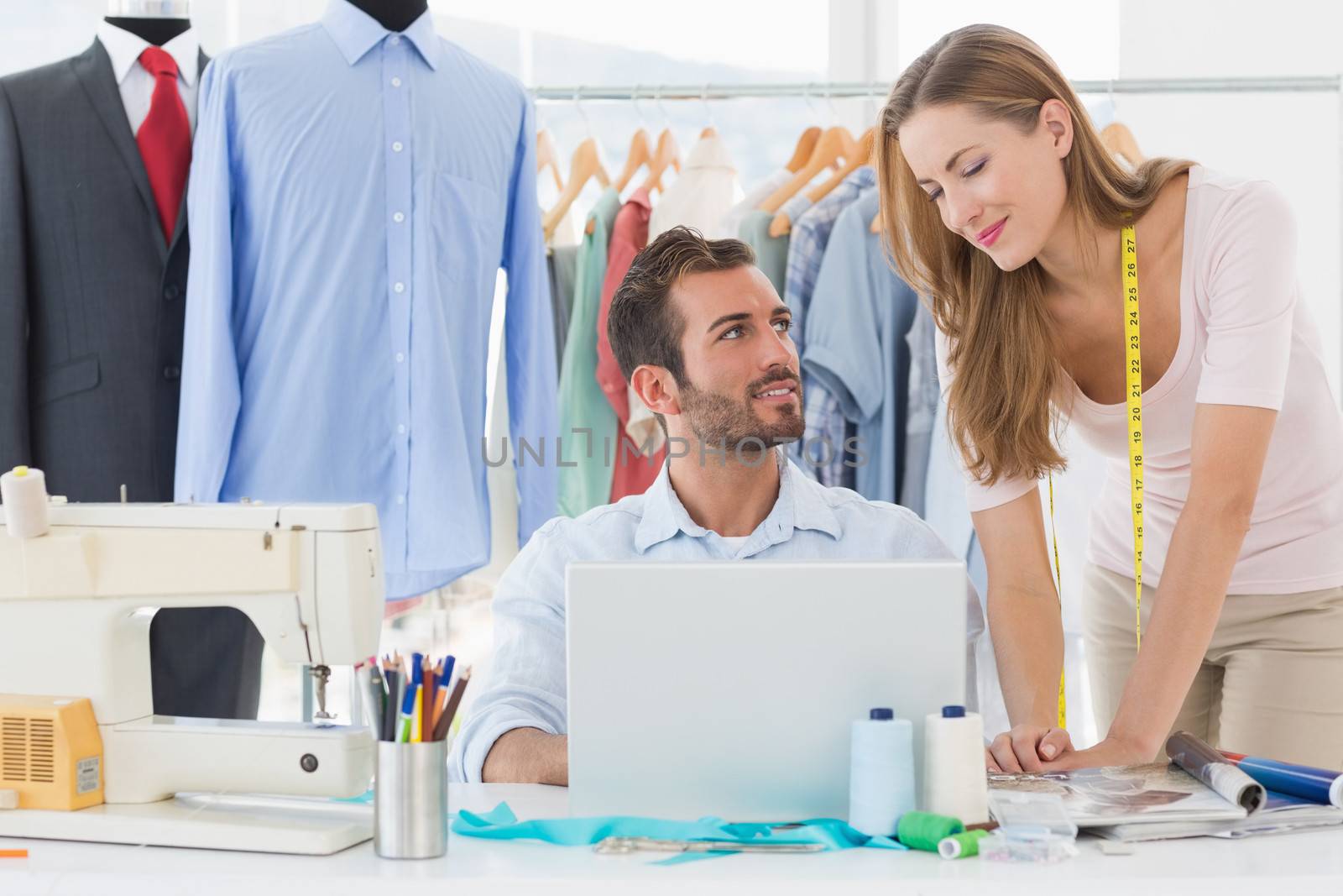 Male and female fashion designers using laptop at work in a studio