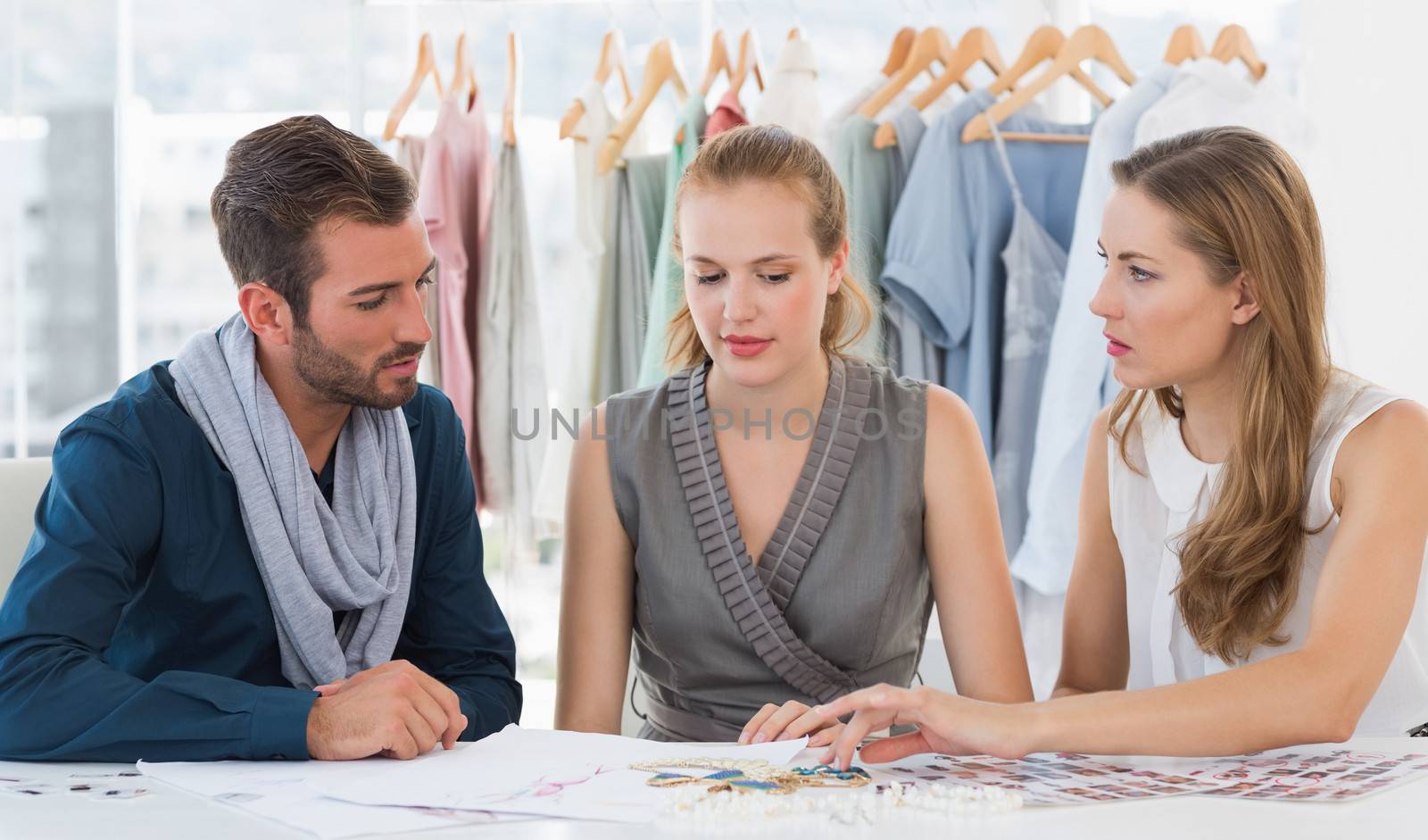 Three fashion designers discussing designs by Wavebreakmedia