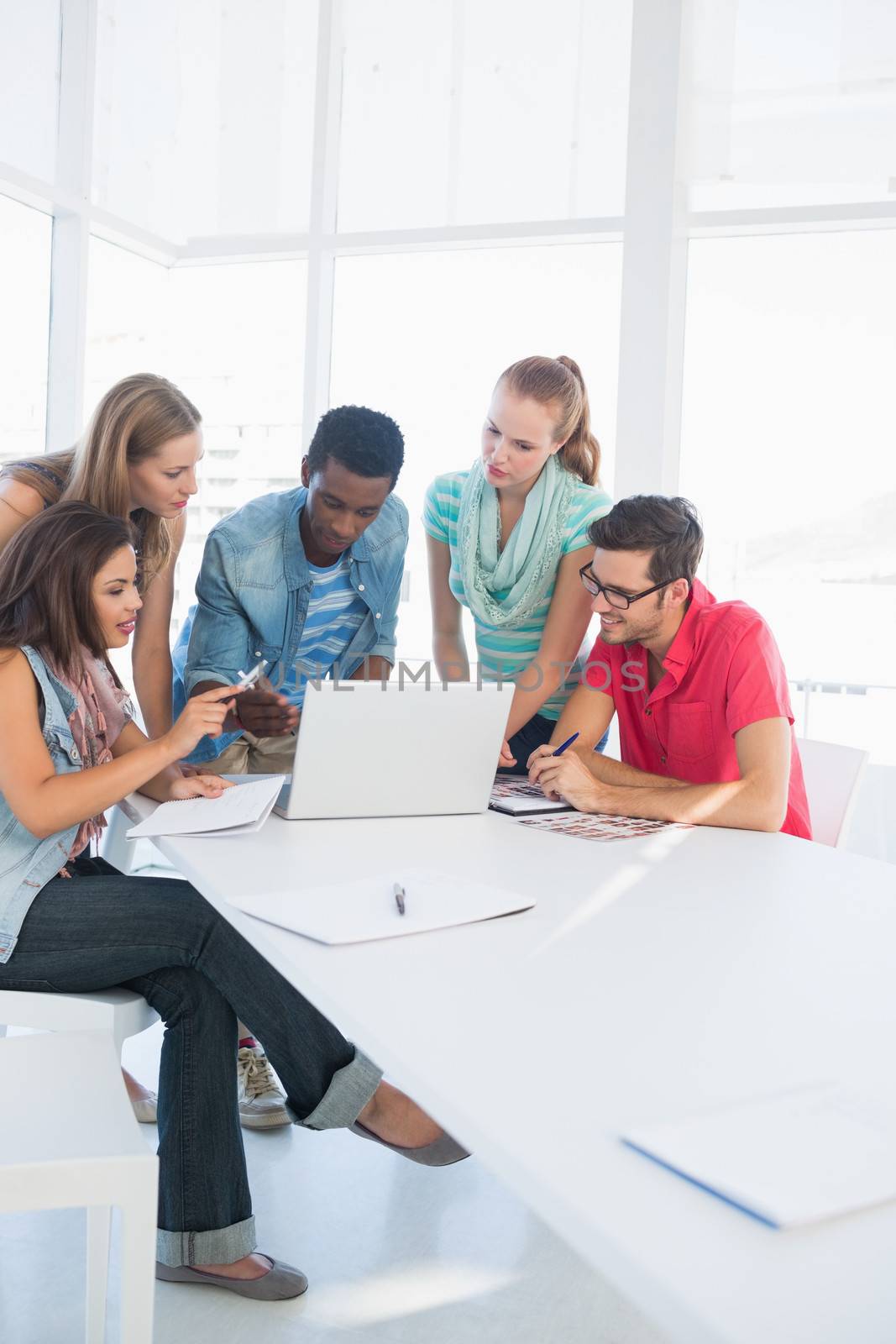 Group of young casual people using laptop in a bright office