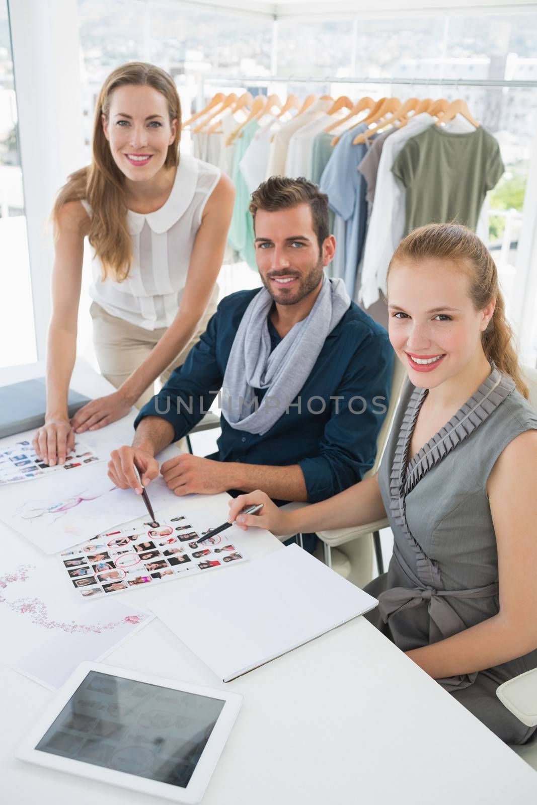 Portrait of three fashion designers discussing designs in a studio