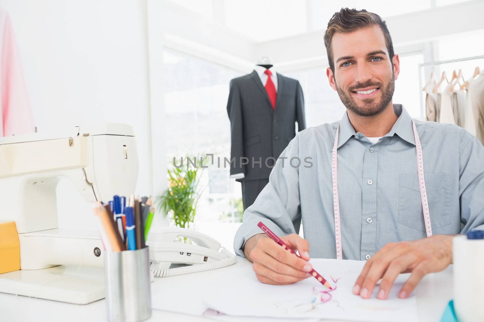 Young male fashion designer working on his designs in the studio